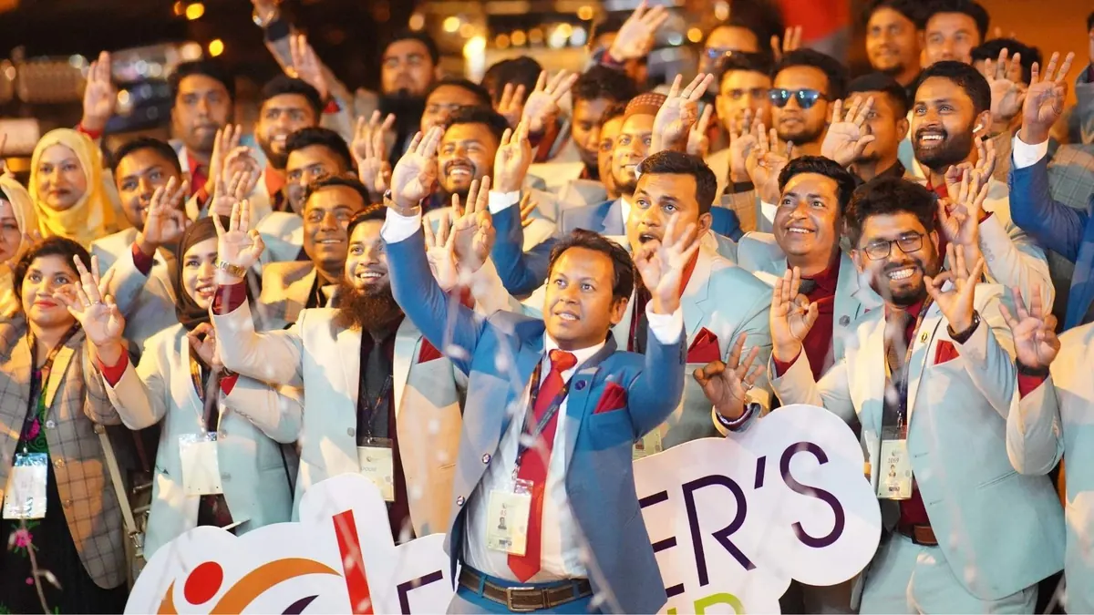A hall of participants with their hands raised at the end of a session