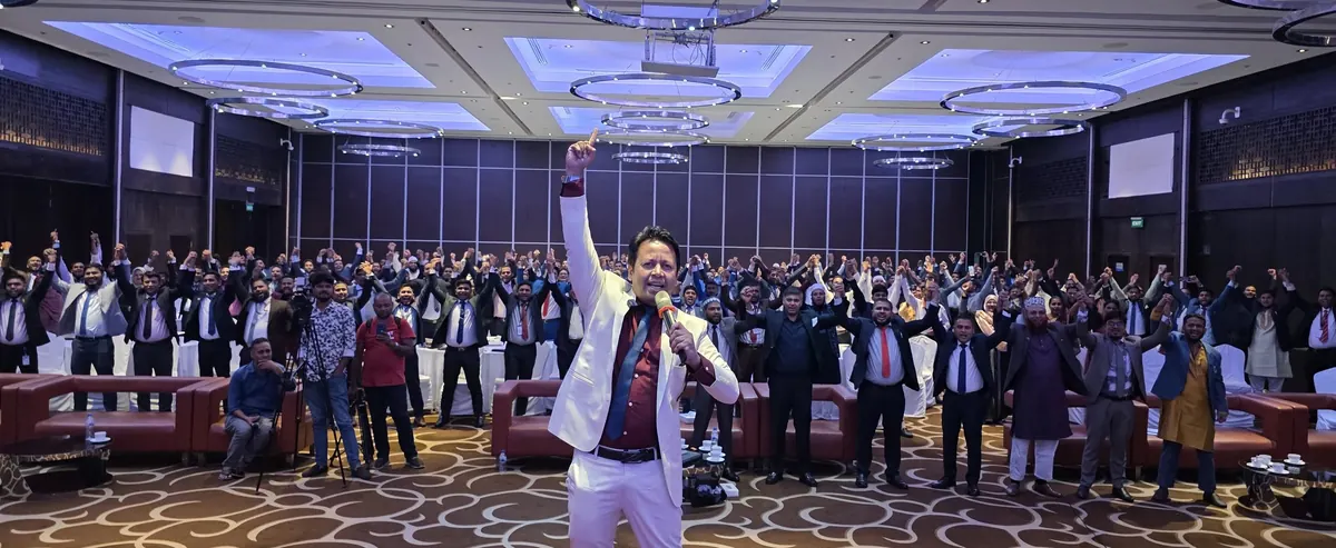 Addressing a full training hall from the floor, microphone in hand